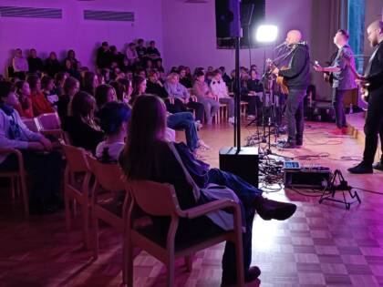 Kuva konsertin yleisöstä, taustavalo on värjännyt huoneen violetiksi