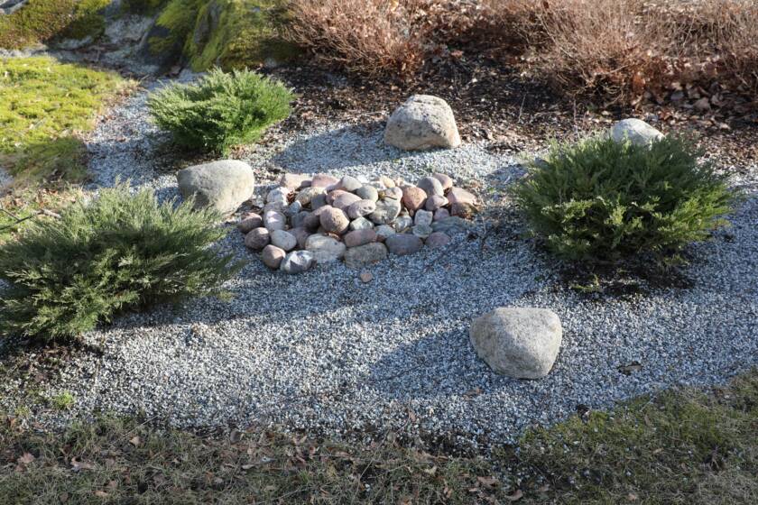 Hautausmaan muistolehdon sirottelupaikka. Kiviä ja kasvillisuutta.