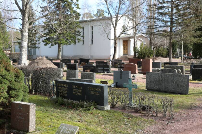 Hautakivet rivissä hautausmaalla, taustalla siunauskappeli.
