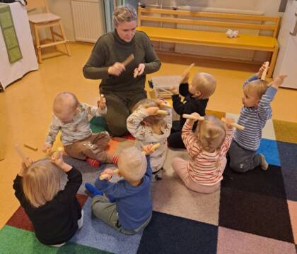 Kuvassa aikuinen ja lapsia soittamassa kapuloilla.