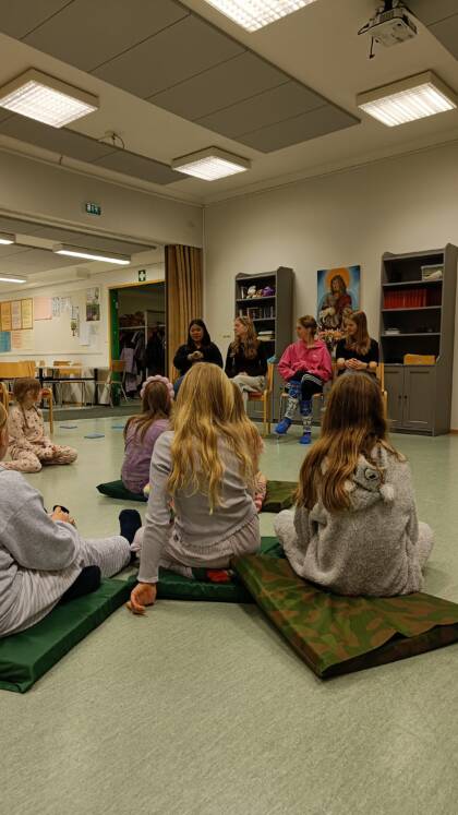 Kouluikäisiä katsomassa isosten esittämää sketsiä leirin iltaohjelmassa