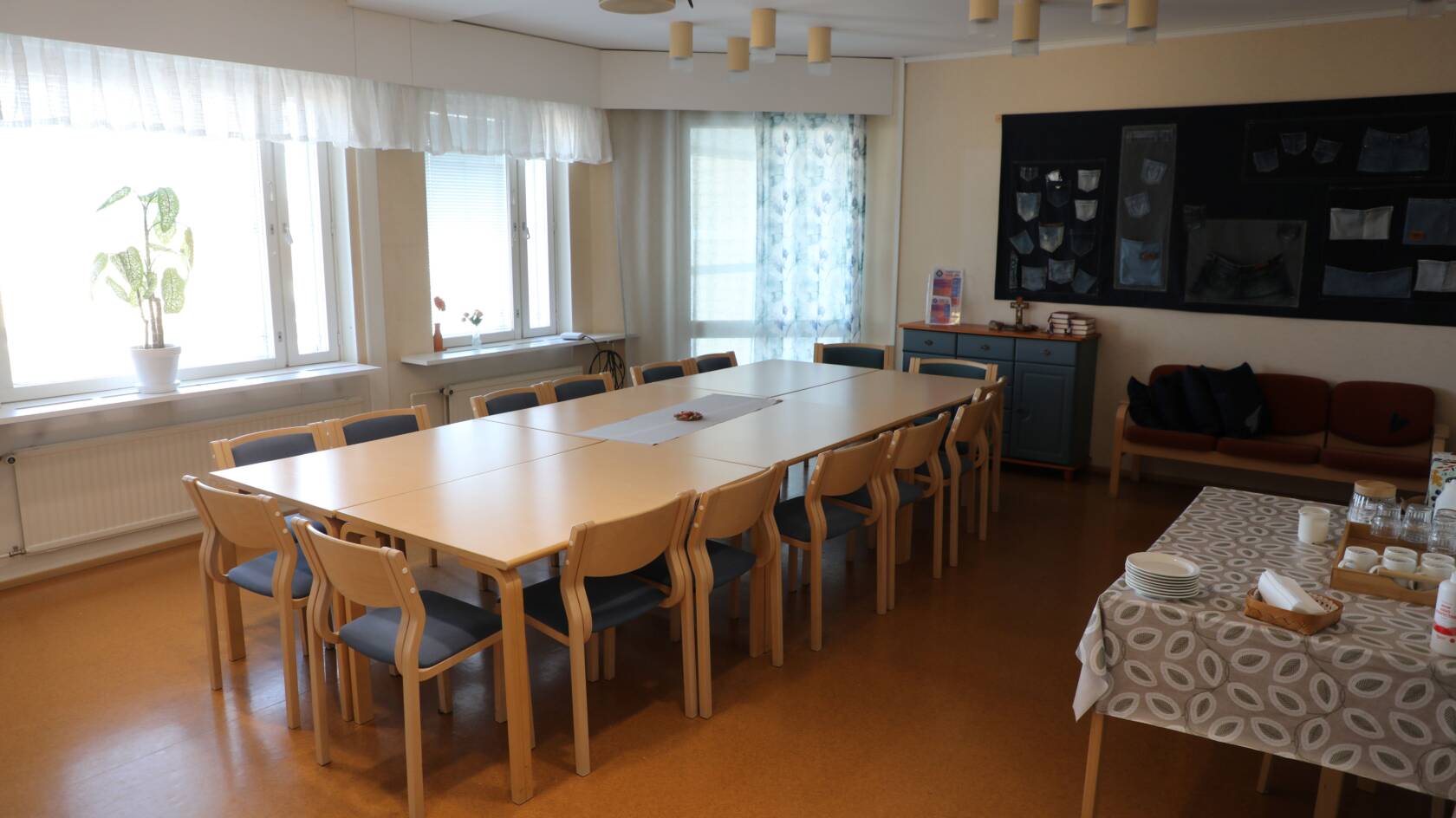 Kokouspöytäryhmä keskellä huonetta, sivussa tarjoilupöytä.