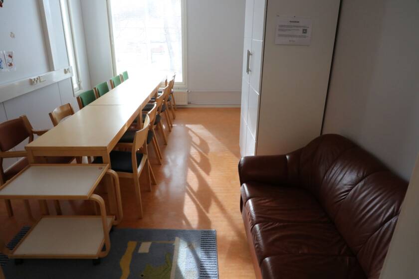 Pitkä kokouspöytäryhmä, edessä ruskea nahkasohva.
