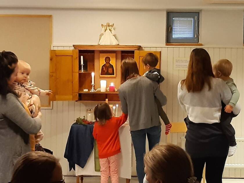 kuvassa lapsia ja aikuisia perhekerhossa alttarin vieressä seisomassa.