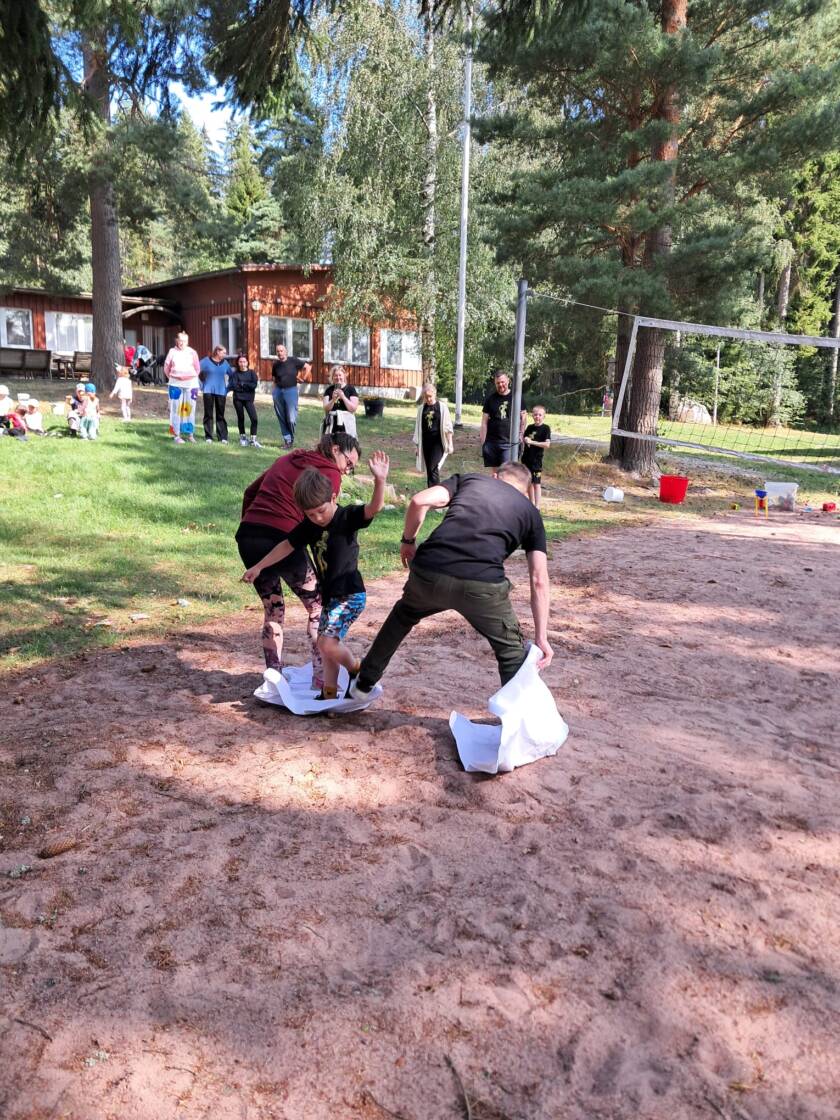 Kuvassa perheitä perheleirillä ulkona suorittamassa olympialaisten yhtä lajia.